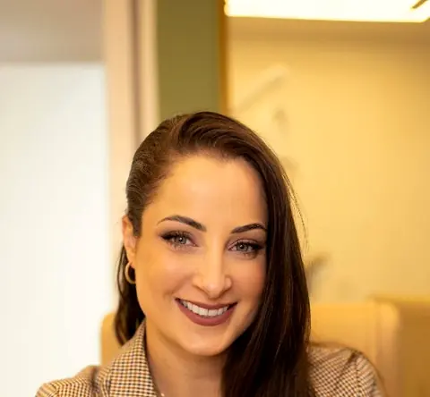 Dra. Érica Possamai sorrindo, de blazer xadrez